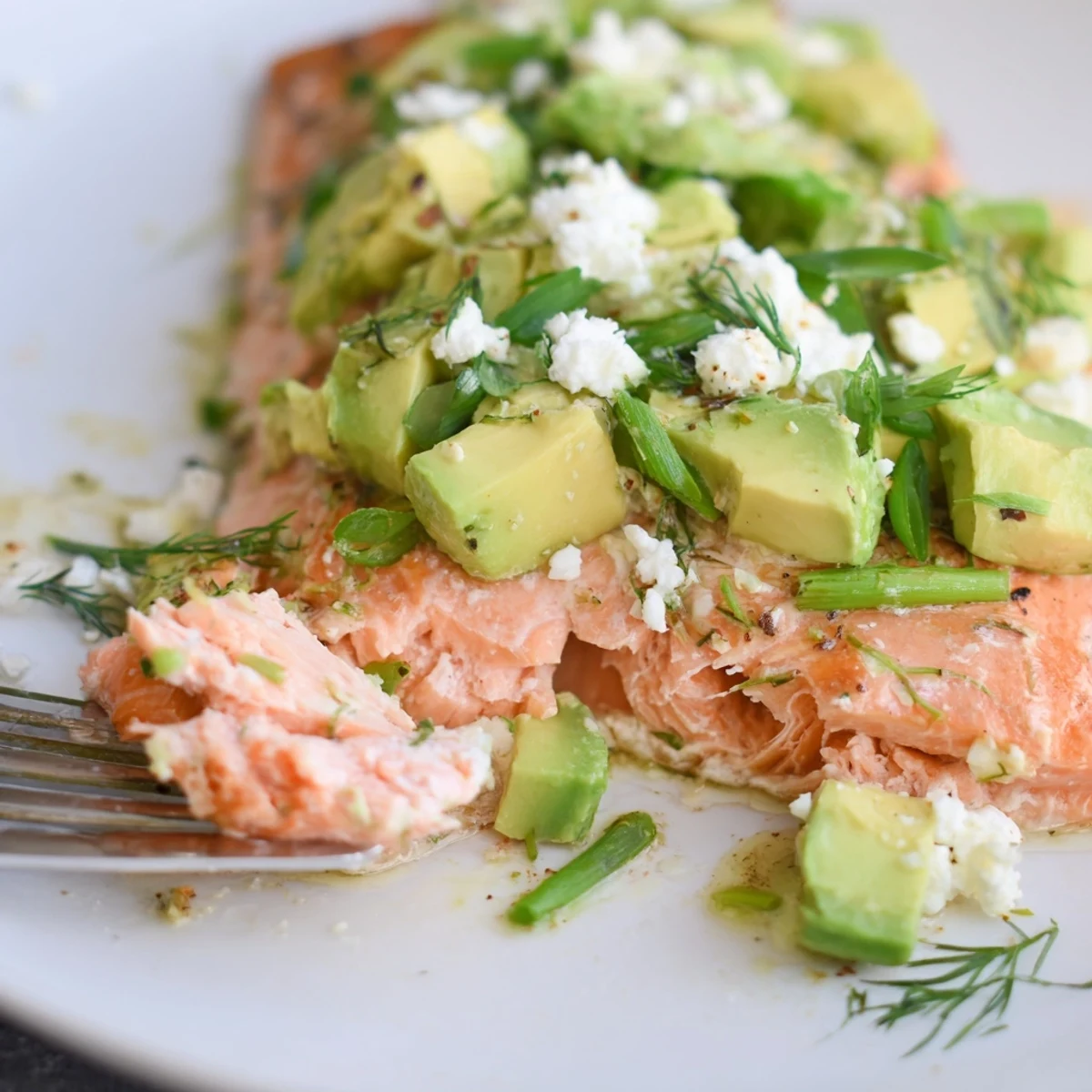 Succulent baked salmon fillets topped with fresh avocado-feta mix, perfect for a healthy meal.  