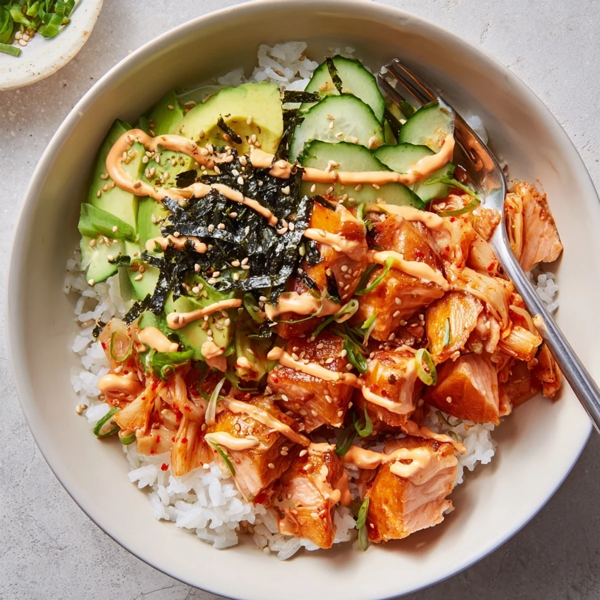 Crispy Salmon Rice Bowl garnished with spicy mayo, fresh avocado, and kimchi.  