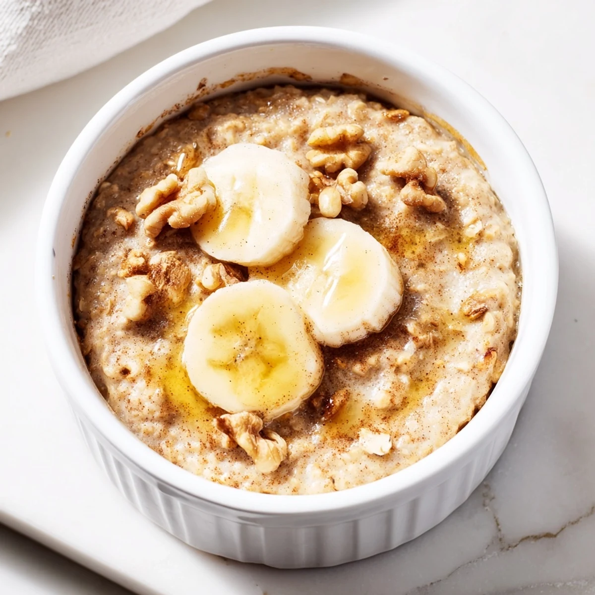 Individual baked oats ramekins with banana and honey, glistening from a delicate honey drizzle.