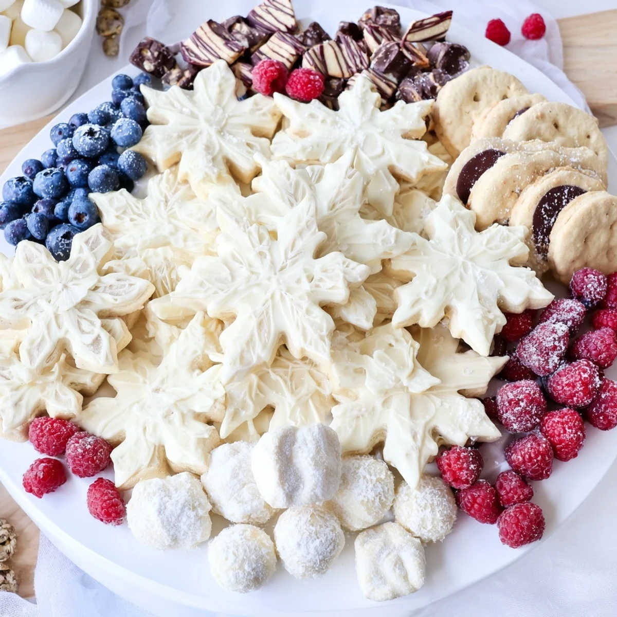 Imagine a snowy Snowflake Dessert Board, overflowing with cookies, chocolates, and colorful fresh fruit.