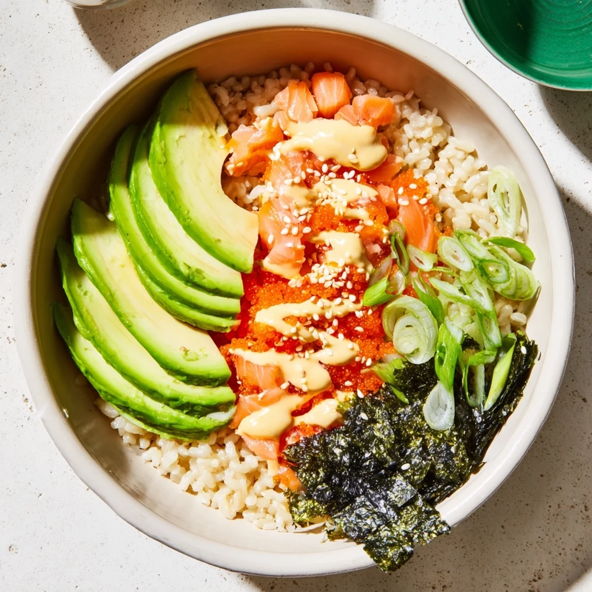 A comforting Emily Mariko Salmon Rice Bowl features warm rice, savory salmon, spicy drizzle, and fresh avocado, perfect for a quick, customizable Japanese-American dinner.