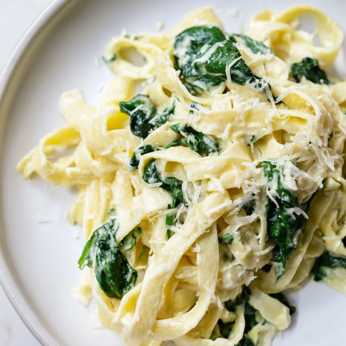 Freshly cooked fettuccine tossed in a creamy garlic sauce with wilted spinach and Parmesan garnish.  