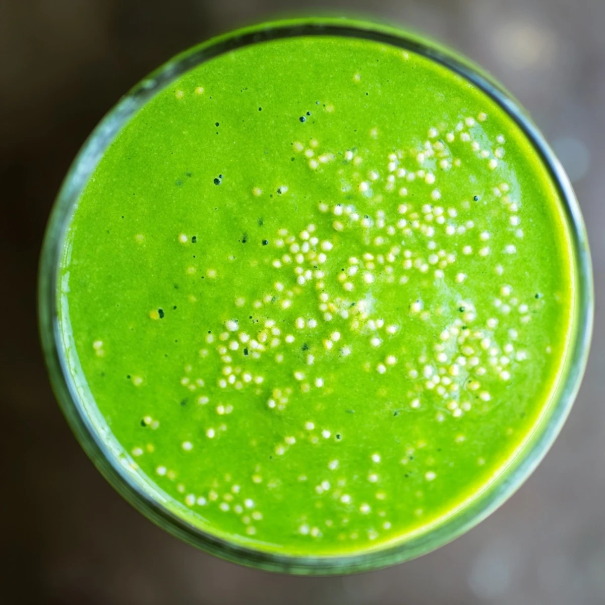 Close-up of a creamy Green Detox Smoothie being poured, showcasing its rich green hue and frothy texture.