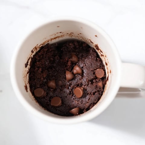 Fluffy Microwaved Mug Cake with melted chocolate chips, ready for a delicious dessert.