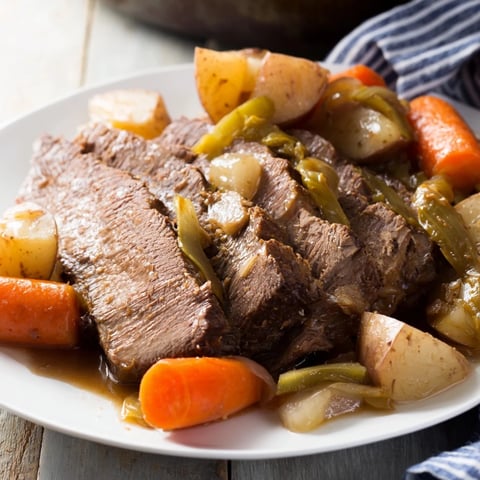 A close-up shot of steaming Pickle Brine Pot Roast with tender vegetables, ready to serve.