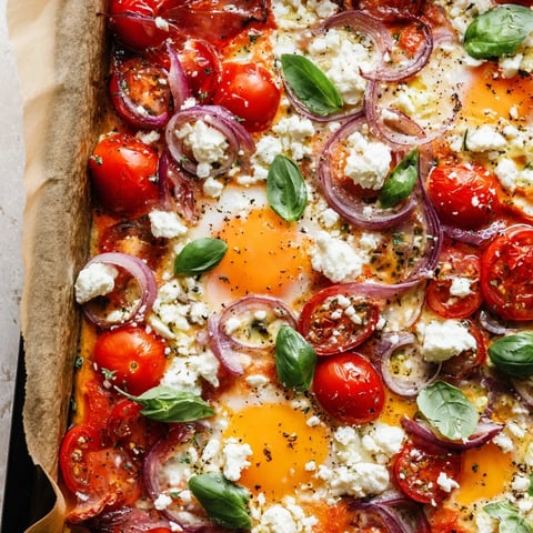Sheet pan Tomato Feta Baked Eggs: a colorful brunch with soft yolks and crumbled feta cheese.