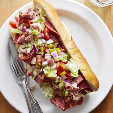 A close-up of a loaded chopped Italian grinder sandwich, with diced salami and provolone nestled in a crisp toasted hoagie roll.