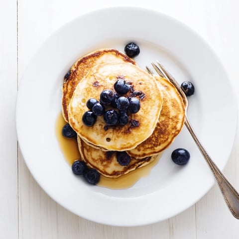 Fluffy cottage cheese pancakes stacked high, drizzled with maple syrup and fresh berries for a protein-packed breakfast.  