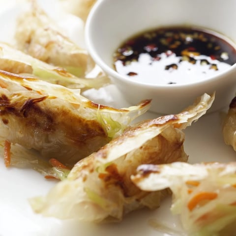 Golden-brown Crispy Rice Paper Dumplings filled with savory meat or vegetables, served with a small dipping bowl of tangy soy sauce.