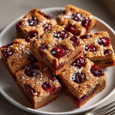 Fudgy Salted Brown Butter Blondies recipe with bright red cherries, ready to slice & serve.