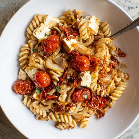 Deliciously baked feta pasta topped with fresh basil, offering savory Mediterranean flavors.  