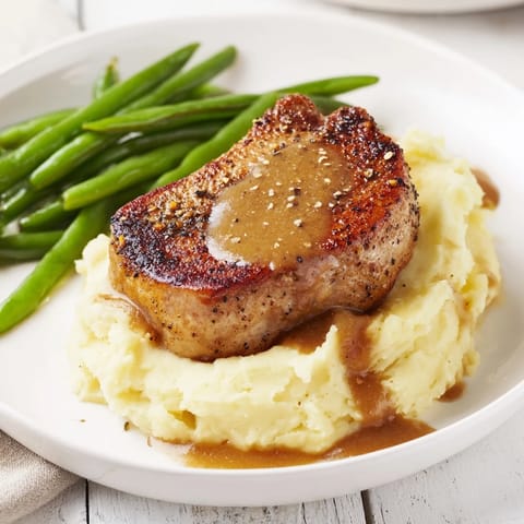 A delicious close-up reveals a forkful of tender Pork Chops & Cheddar Mash Bowl, perfect for a cozy dinner.