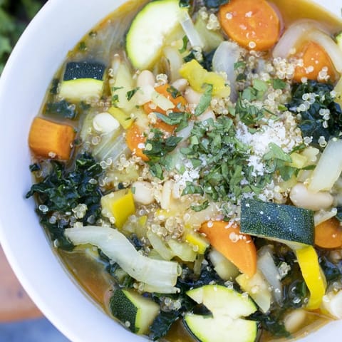 Close-up of a rustic, hearty Minestrone with Quinoa, showing colorful vegetables and beans.