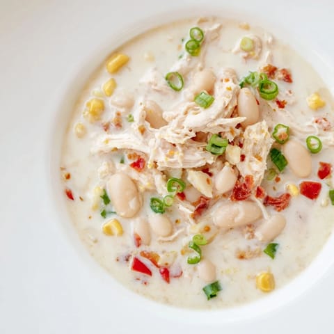 Delicious Creamy White Chicken Chili with Beans, smelling of warm spices, is simmering on the stovetop.
