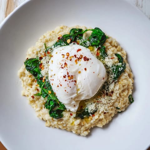 Steaming Savoury Oatmeal with Spinach & Poached Egg piled high, ready to eat for a delicious brunch.