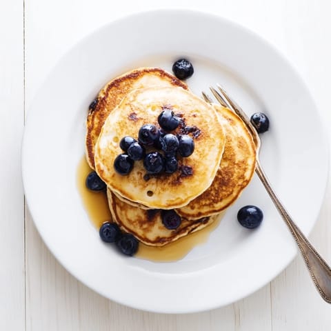 Fluffy cottage cheese pancakes stacked high, drizzled with maple syrup and fresh berries for a protein-packed breakfast.  