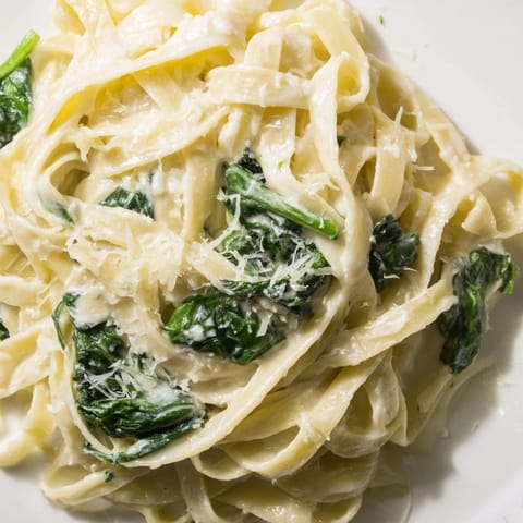 A warm skillet of creamy garlic spinach pasta garnished with parsley, served as a comforting vegetarian dinner.  
