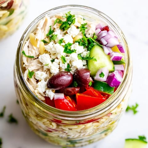 Vibrant Mediterranean salad jars feature feta, cherry tomatoes, and crisp cucumbers, ideal for grab-and-go lunches.