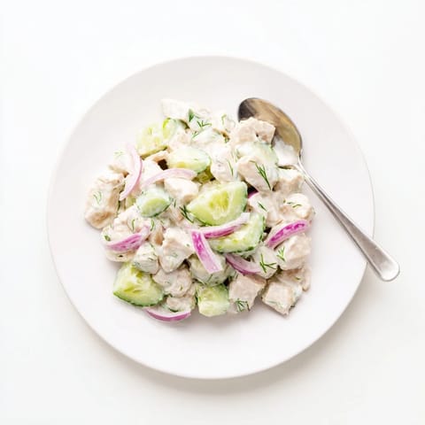 Creamy Cucumber Chicken Salad in a glass serving bowl topped with chopped green onions, a side of crackers, and a linen napkin, perfect for a refreshing high-protein lunch.