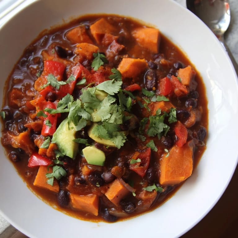 Hearty sweet potato & black bean chili simmering, showcasing tender sweet potatoes and flavorful spices.