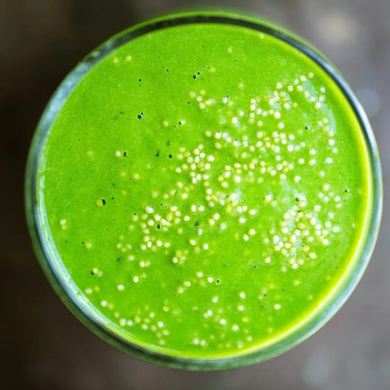 Close-up of a creamy Green Detox Smoothie being poured, showcasing its rich green hue and frothy texture.