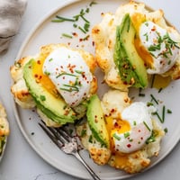 Light, golden Cloud Bread Breakfast Clouds topped with creamy avocado slices and a perfectly poached egg.