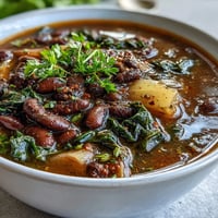 A steaming bowl of Soul Food Black-Eyed Pea and Collard Green Stew with tender greens and smoky broth, perfect for a cozy Southern dinner.